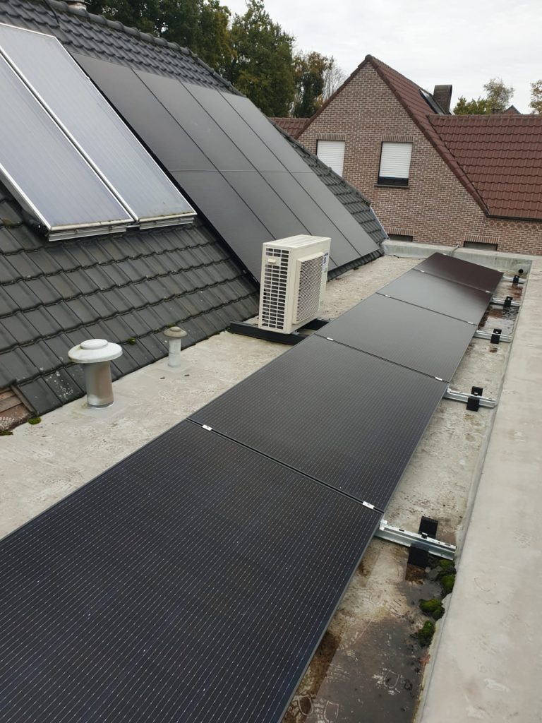 Zwarte zonnepanelen op plat dak naast woninginstallatie